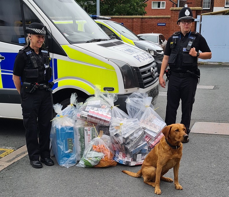 Two police officers with a dog and seized contraband  