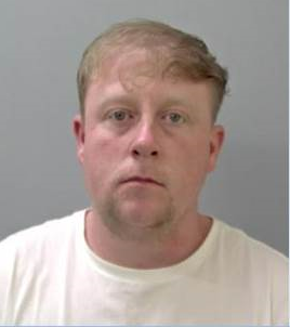 White man with fair hair in a white T-shirt