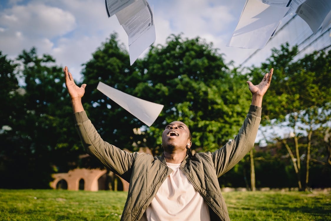 A male student throwing his A Level results in the air with glee