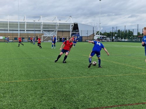 Action shot of a West Mercia Police (North) player trying to get the ball from a Shrewsbury fan players