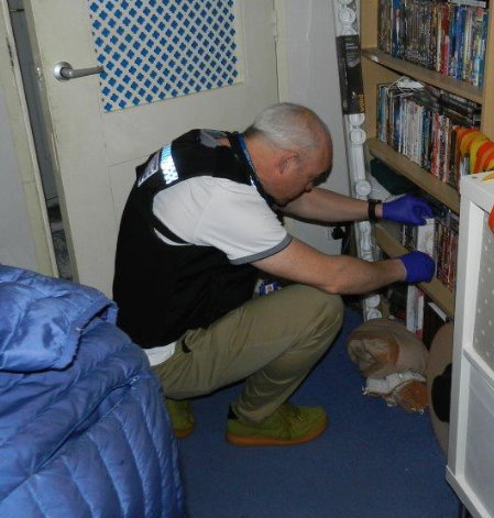 Officer searching bookshelf in house