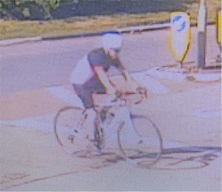 Male cyclist on road bike, wearing black and white top, black shorts and a white bike helmet