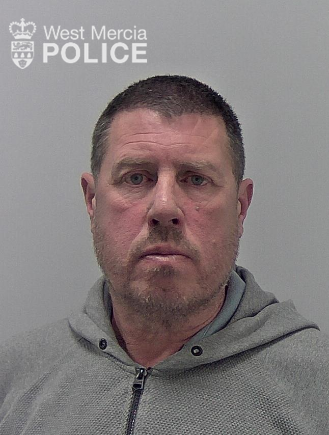 54 year old man with short dark hair, serious look, wearing a grey hoodie
