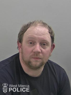 White man with light brown beard, brown receding hair and an eyebrow piercing