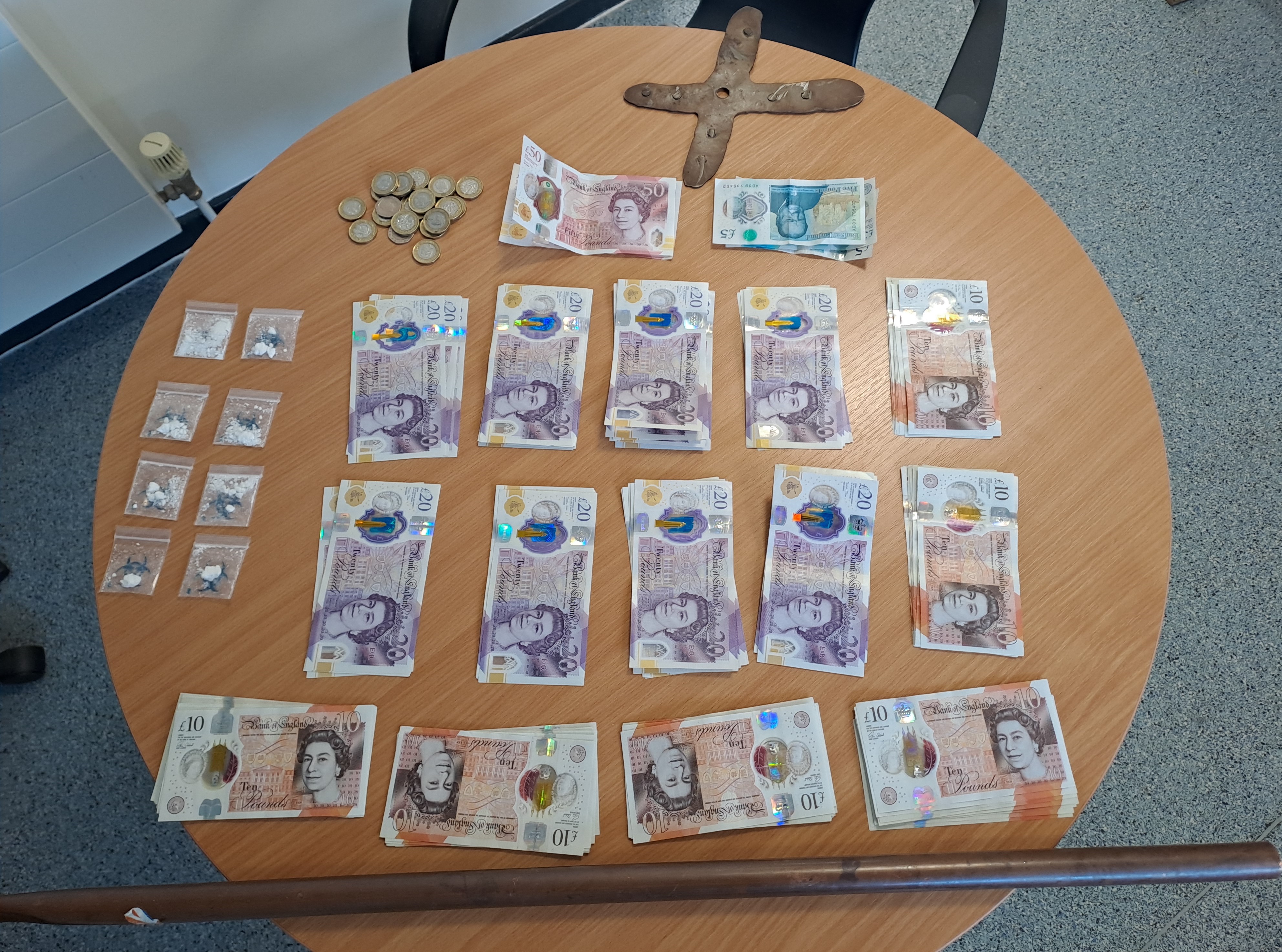 A table with drugs, cash and a weapon on it