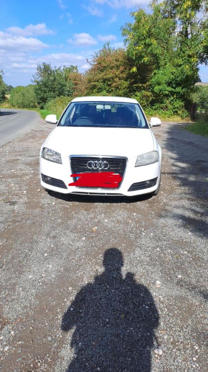 A white Audi car parked on the roadside
