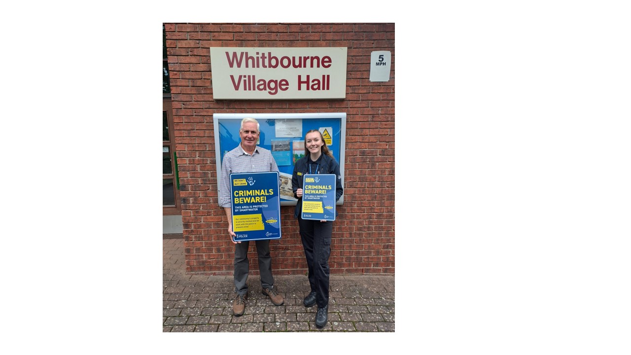 Two people holding we dont buy crime signs smiling at the camera