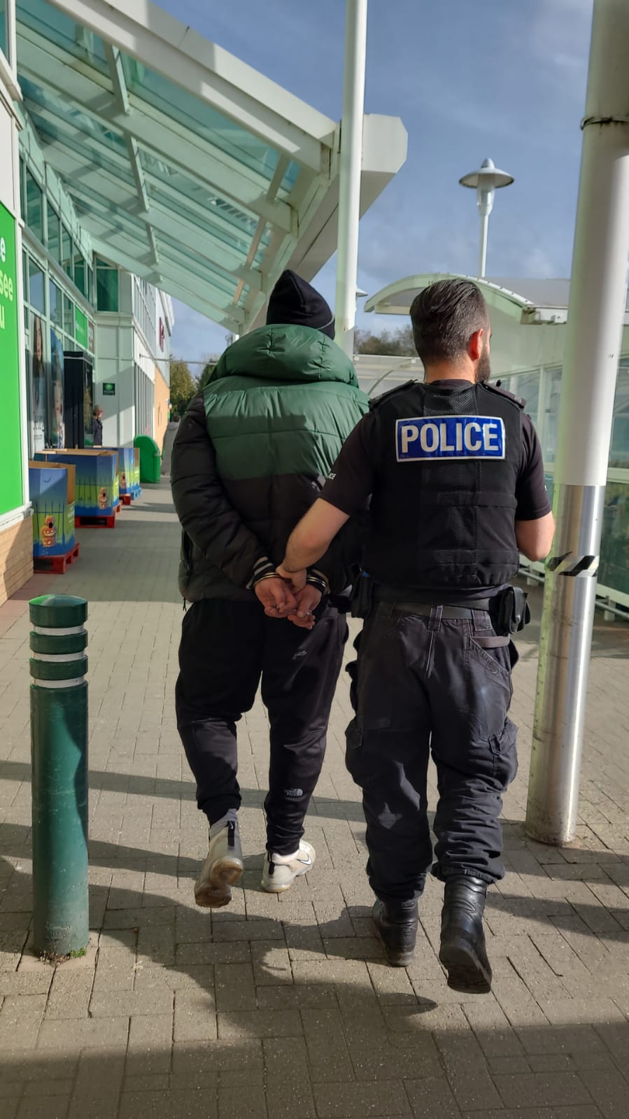 Man arrested for theft being led away by police