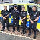 Police officers stood in front of police van.