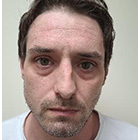 Man with brown hair wearing white shirt. He has a beard.