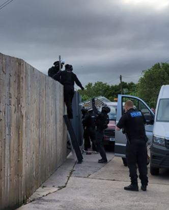 Police officers going over a fence. 