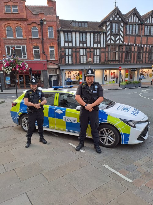 two police officers with police car in town centre
