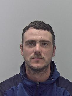 White male, short brown hair and blue jumper. 