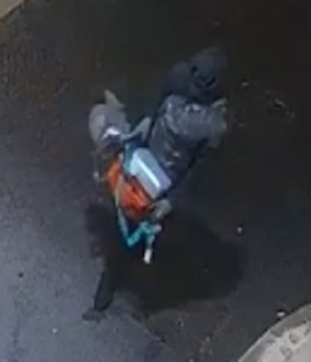suspect dressed all in black holding an orange angle grinder