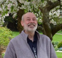 White man, with white hair and beard with a big smile. 