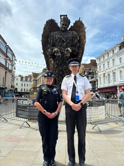 Two police officers stood in front of knife angel. 