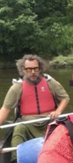 White male, dark glasses and long brown hair. 