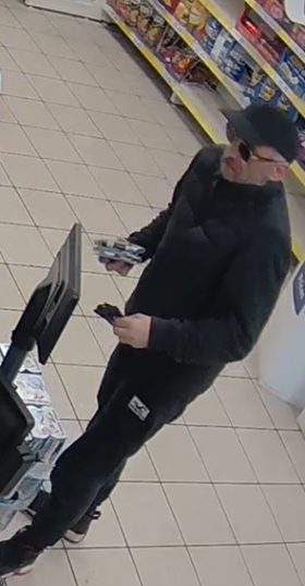 White male, wearing a black cap in a shop. 