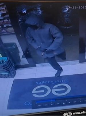 Masked man in grey coat walking into service stations.