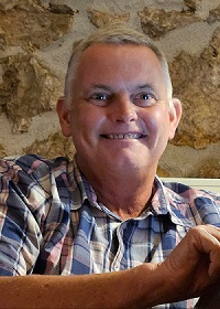 White male, grey hair, dark eyes and checked shirt.