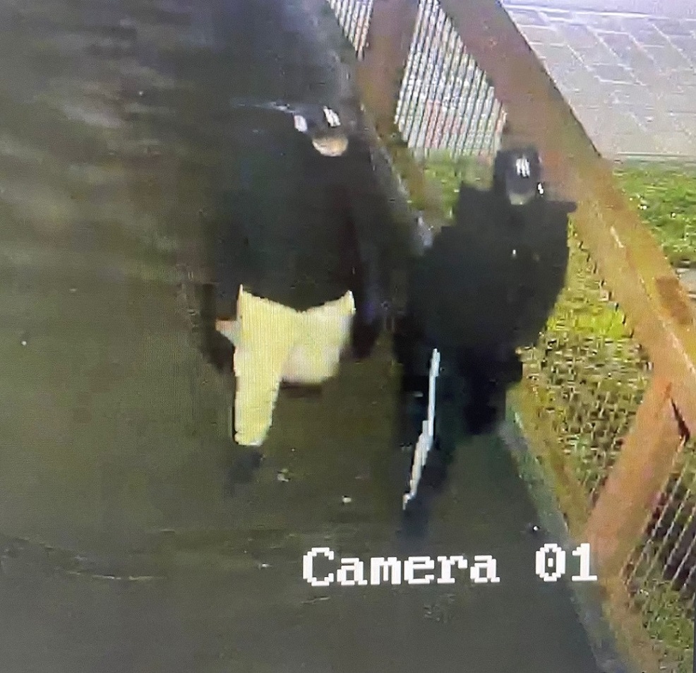 two persons wearing black coats with hats and face coverings