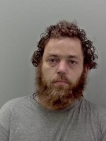 White male with long, curly brown hair and long beard. 