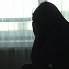 A silhouette of a woman with her head in her hands